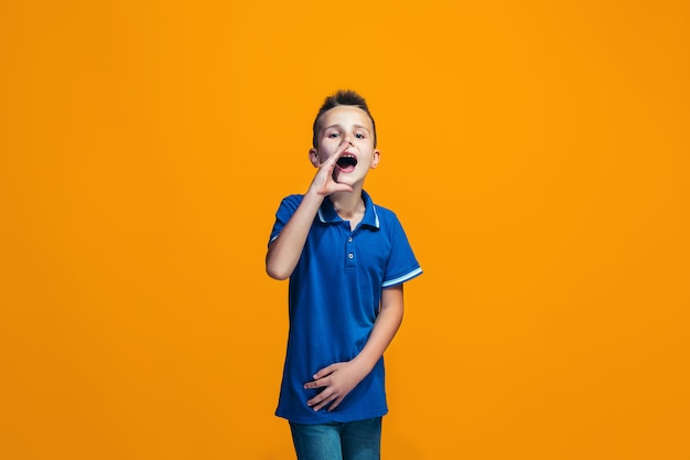 Isolated on orange young casual teen boy shouting