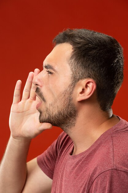 Isolated on red young casual man shouting