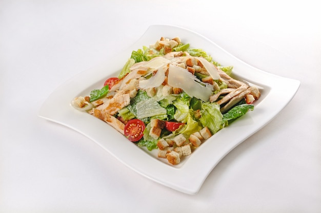 Isolated shot of a white plate with Ceasar salad - perfect for a food blog or menu usage