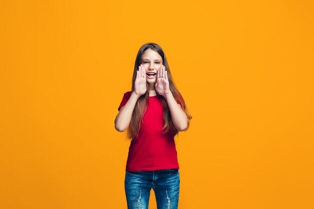 Isolated on yellow young casual teen girl shouting at studio