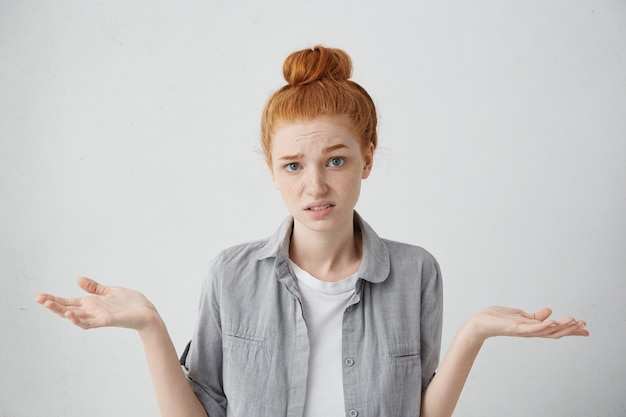 Free Photo it's not a big deal. clueless young woman dressed in casual clothing shrugging shoulders and staring with confused look