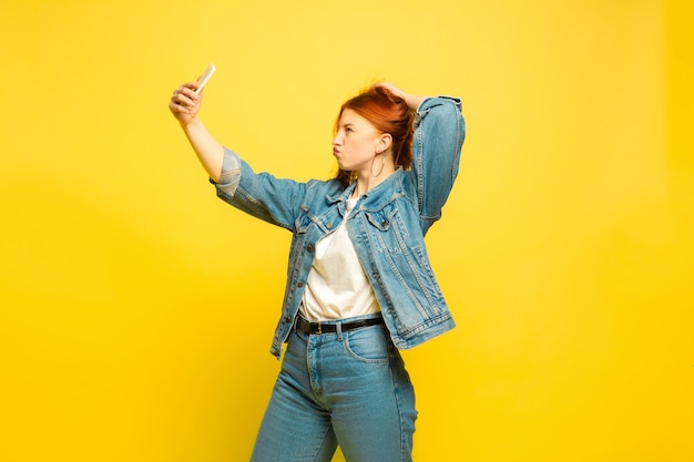 It's easier to be follower. Need minimum clothes for selfie. Caucasian woman's portrait on yellow background. Beautiful female red hair model. Concept of human emotions, facial expression, sales, ad.