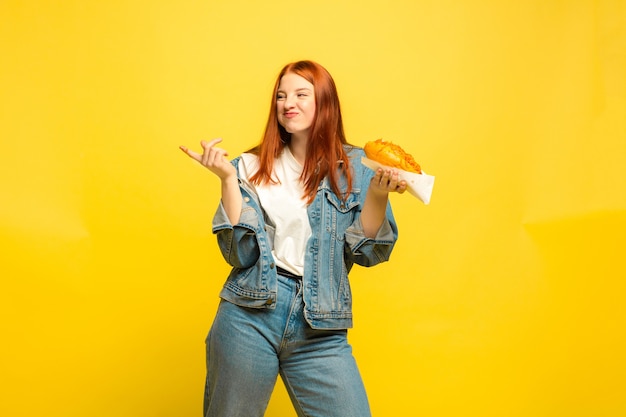 It's easier to be follower. Don't need to take photo with food. Caucasian woman's on yellow background. Beautiful female red hair model. Concept of human emotions, facial expression, sales, ad.