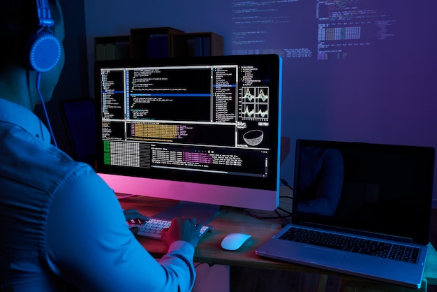 Free photo it specialist checking code at computer in the dark office at night