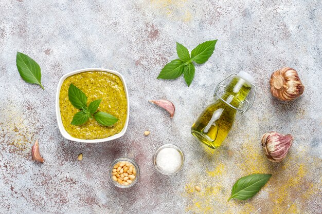 Italian basil pesto sauce with culinary ingredients for cooking.