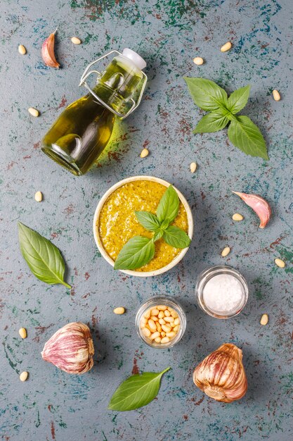 Italian basil pesto sauce with culinary ingredients for cooking.