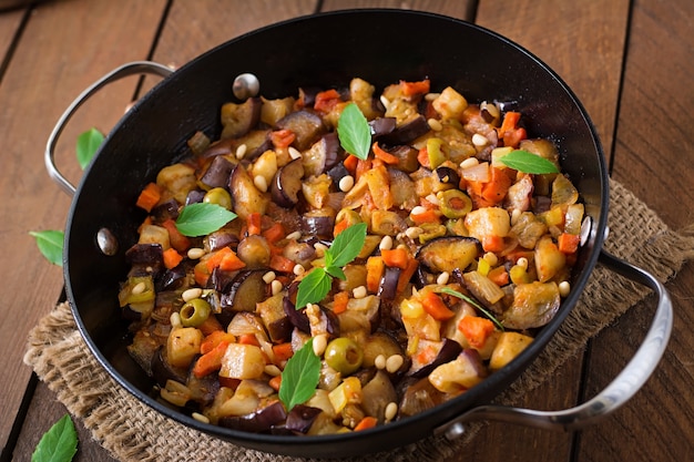 Italian Caponata with frying pan on a wooden table