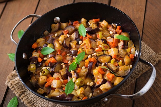 Italian Caponata with frying pan on a wooden table