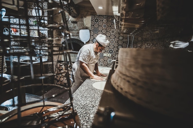 Free Photo italian chef in uniform is preparing pastry for pizza at the kitchen.