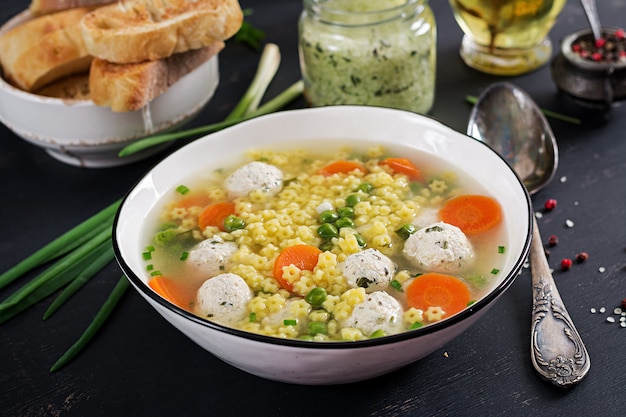 Italian meatball soup and Stelline gluten free pasta in bowl on black table