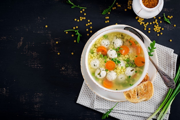 Free photo italian meatball soup and stelline  pasta in bowl on black table.