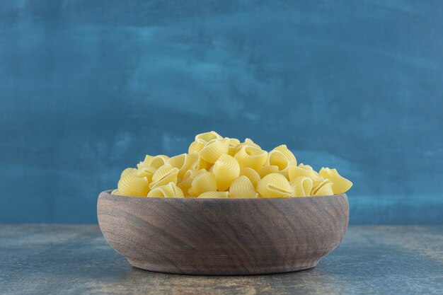 Italian pipe pasta in the bowl, on the marble surface.