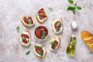 Free photo italian sandwiches - bruschetta with cheese, dry tomatoes and basil.