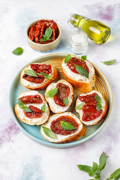 Free photo italian sandwiches - bruschetta with cheese, dry tomatoes and basil.