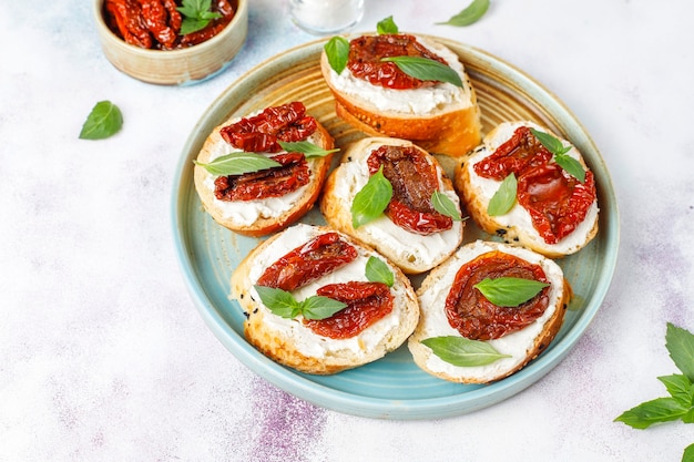 Free photo italian sandwiches - bruschetta with cheese, dry tomatoes and basil.