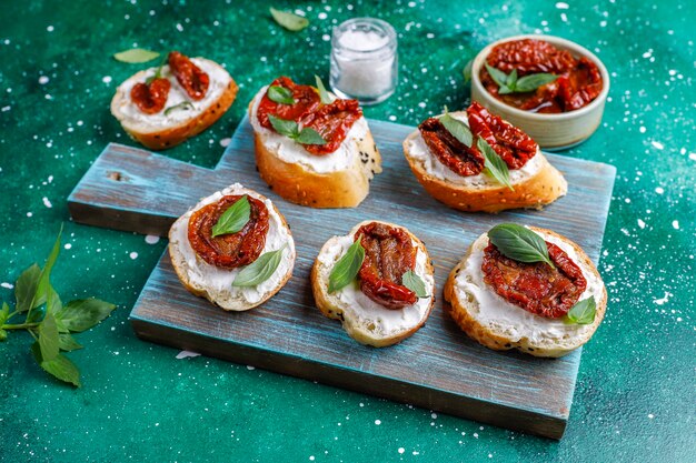 Italian sandwiches - bruschetta with cheese, dry tomatoes and basil.