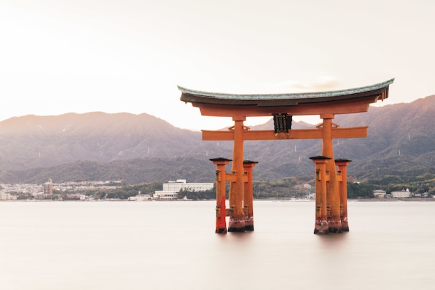 Free photo itsukushima shrine in a lake surrounded by hills covered in greenery in japan