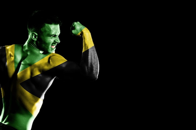 Jamaica flag on handsome young muscular man black background