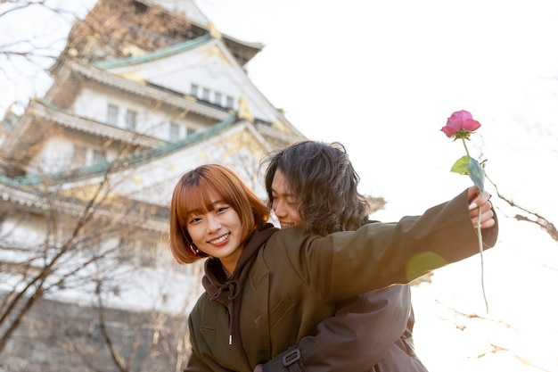 Japanese couple embraced outdoors while girlfriend is holding a rose