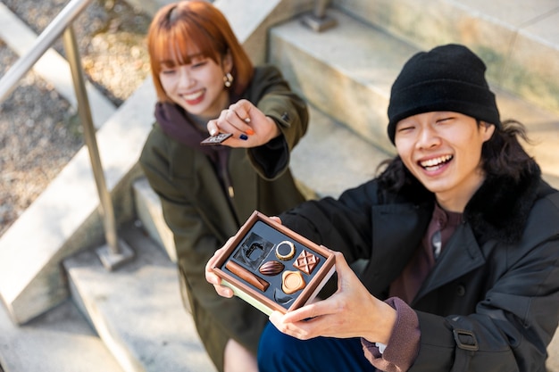 Free photo japanese couple enjoying a date outdoors while eating chocolate sweets