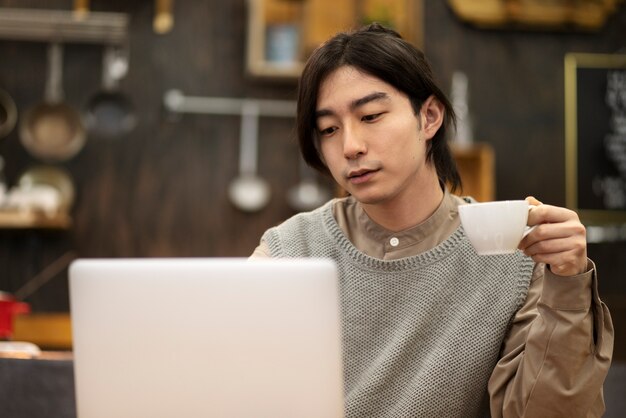 Japanese man drinking coffee and working on his laptop in a restaurant