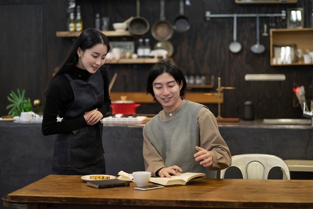 Japanese woman and man reading from notebook in a restaurant