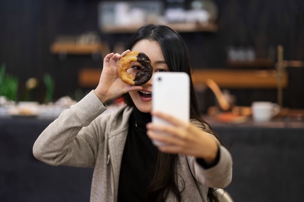 Japanese woman taking selfie with doughnut