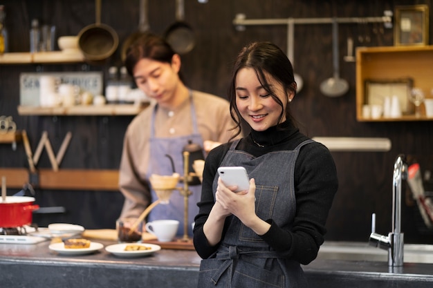 Free photo japanese woman using her smartphone in a restaurant