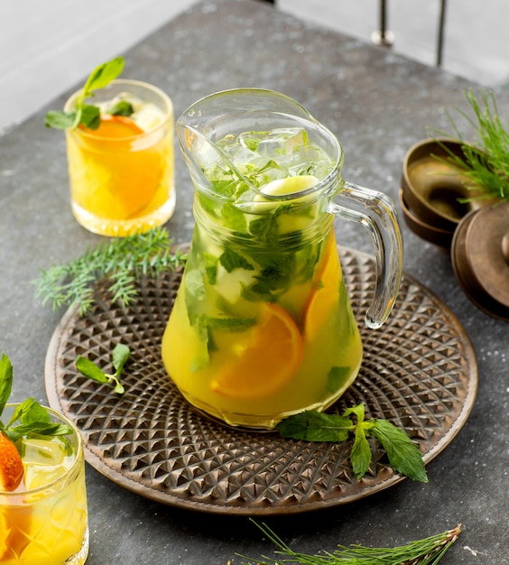 Free Photo a jar of orange mojito drink placed in bronze plate