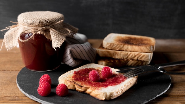 Jar of raspberry jam with bread and knife