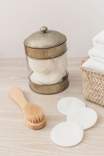 Jar of sponge; brush and towels in basket on wooden surface