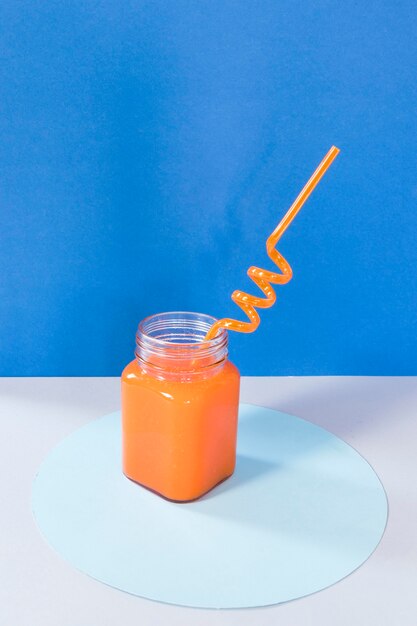 Jar with orange smoothie on table