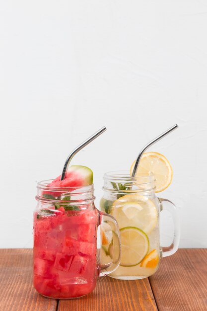 Jars with fresh fruits drinks on table