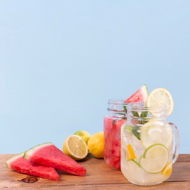 Jars with fresh fruits drinks on table