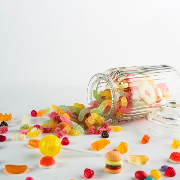 Free photo jelly worms spilled from jar near candies