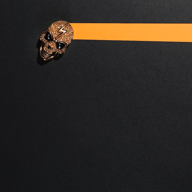 Free Photo jewelry skull with lightning laid on orange stripe of paper