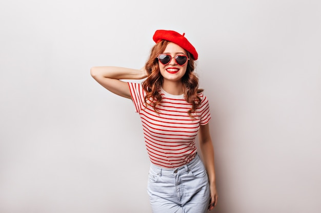 Jocund french girl with pretty smile posing . Indoor shot of romantic red-haired lady wears beret.