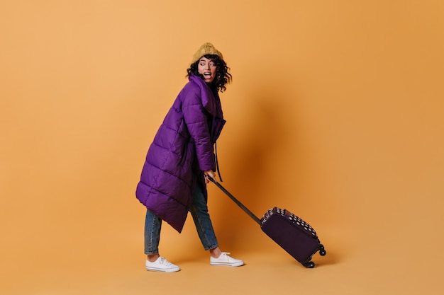 Free photo jocund young woman posing with suitcase