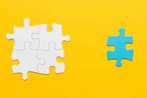 Free photo joint white puzzle with a blue single piece on yellow surface