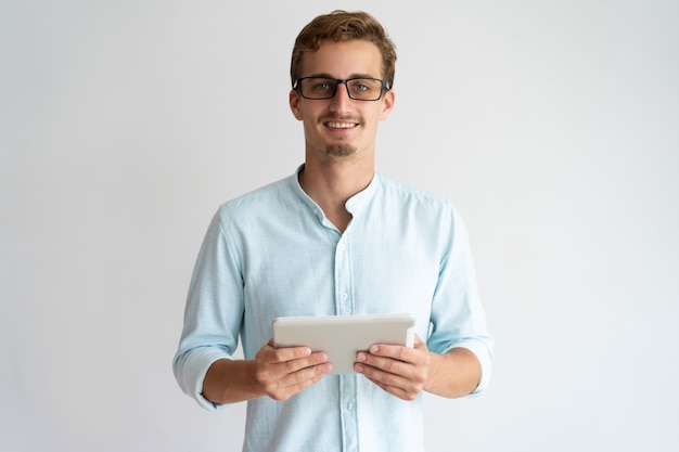 Free photo jolly excited handsome male specialist working with tablet and looking at camera.