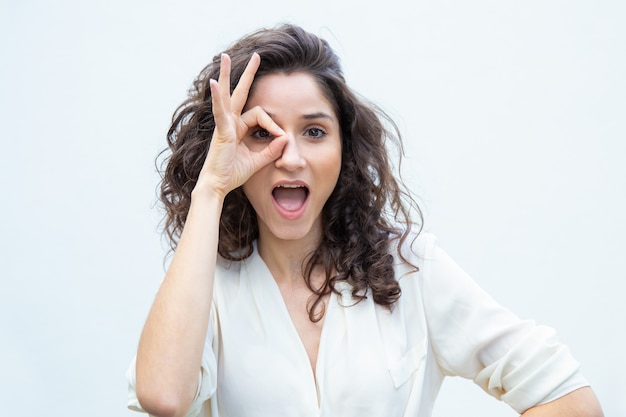 Joyful beautiful woman with open mouth applying hand to eye