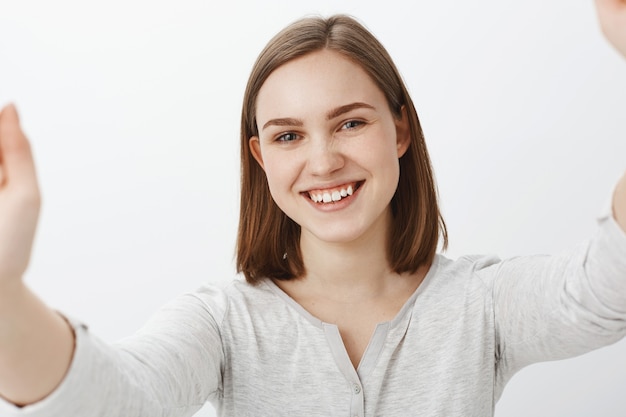 Free photo joyful brunette woman in casual outfit taking selfie and smiling broadly