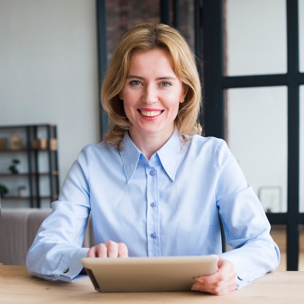 Joyful business woman using tablet at table