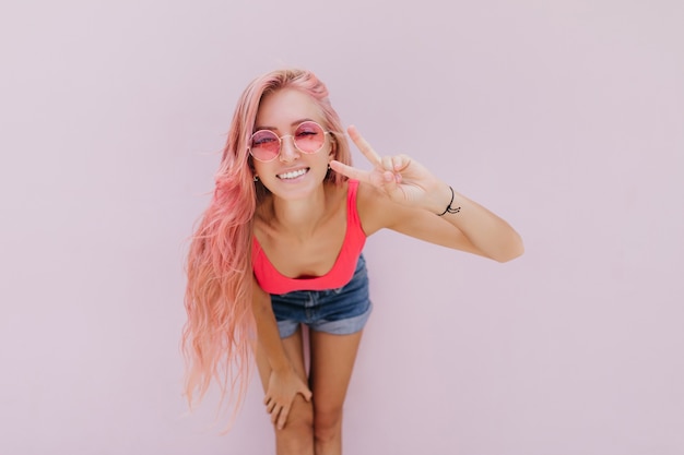 Free photo joyful caucasian woman with pink hair posing with cute smile.