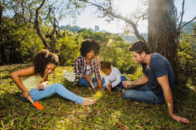 Free photo joyful family sitting under a tree