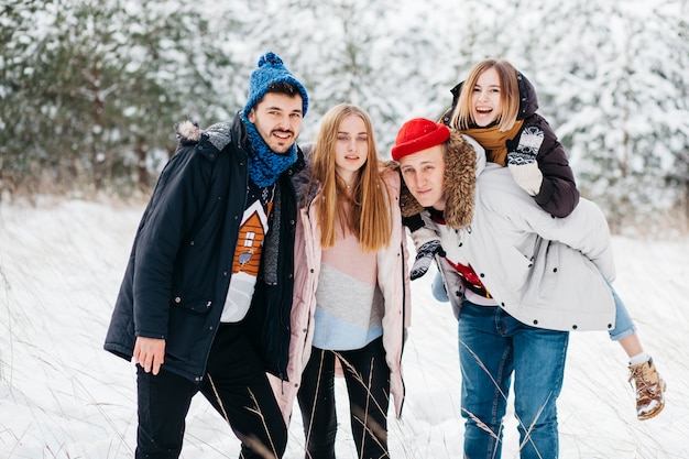 Joyful friends standing in winter forest 