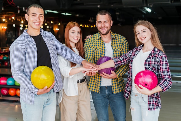 Free photo joyful friends with bowling balls in a bowling club