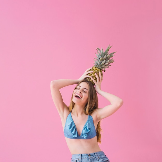 Joyful girl in bikini with pineapple