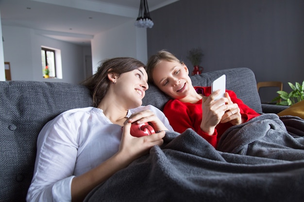 Joyful homosexual girls resting on couch