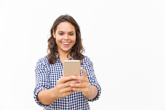 Joyful Latin woman with smartphone watching funny content